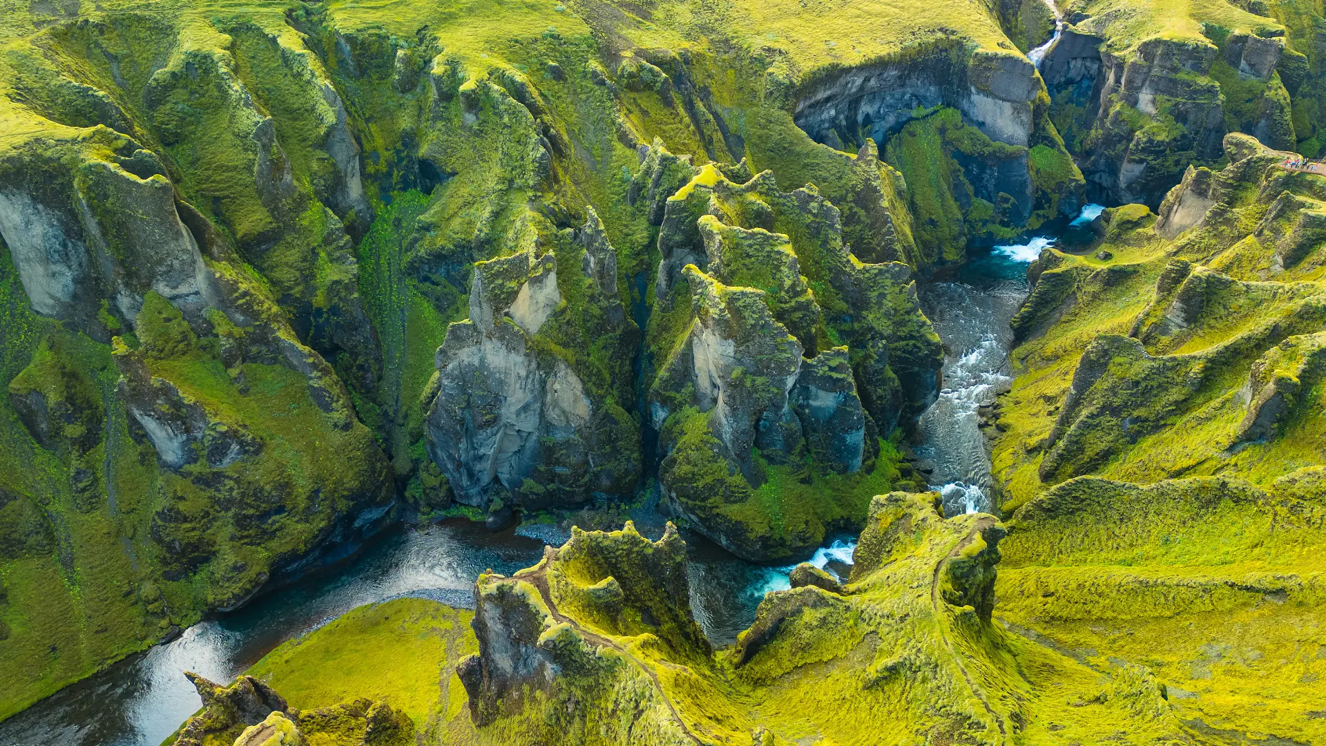Fjaðrárgljúfur canyon in Iceland with moss-covered cliffs and a winding glacial river.