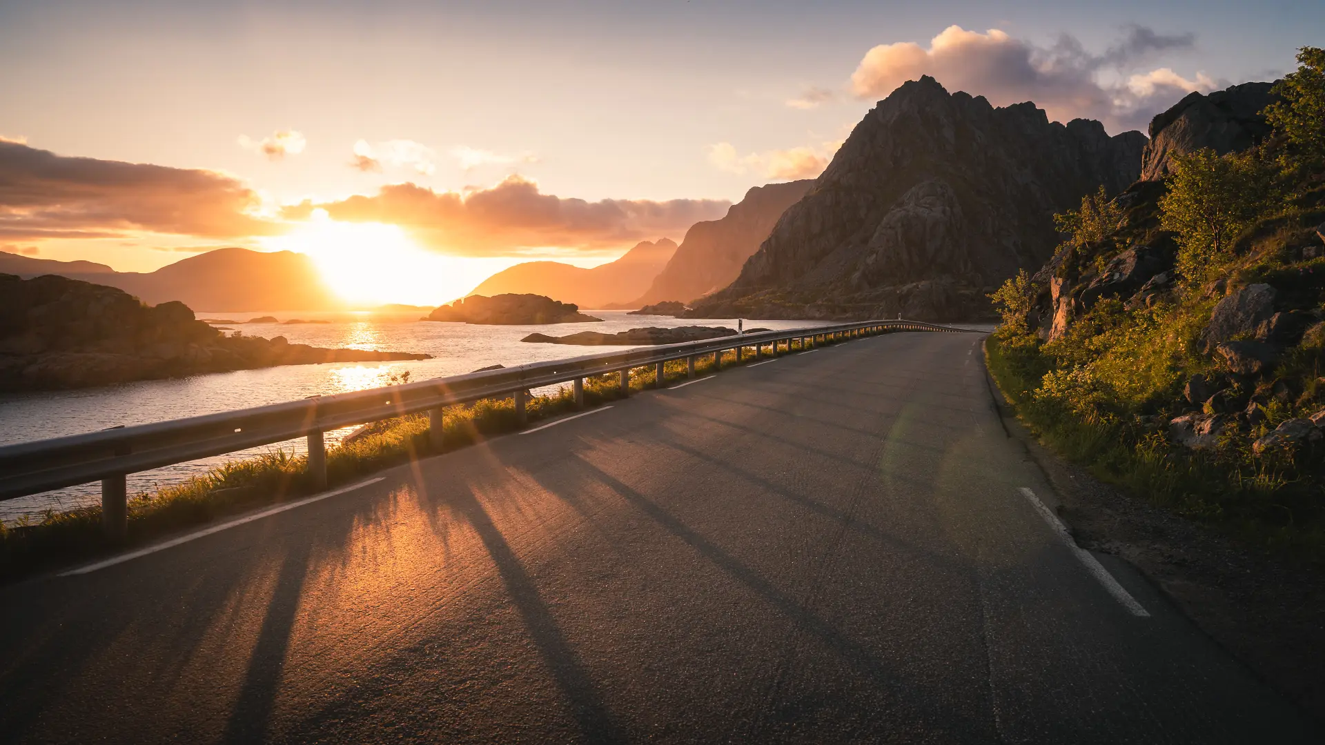 Coastal road winding along the shoreline in the Lofoten Islands, Norway, during sunset.