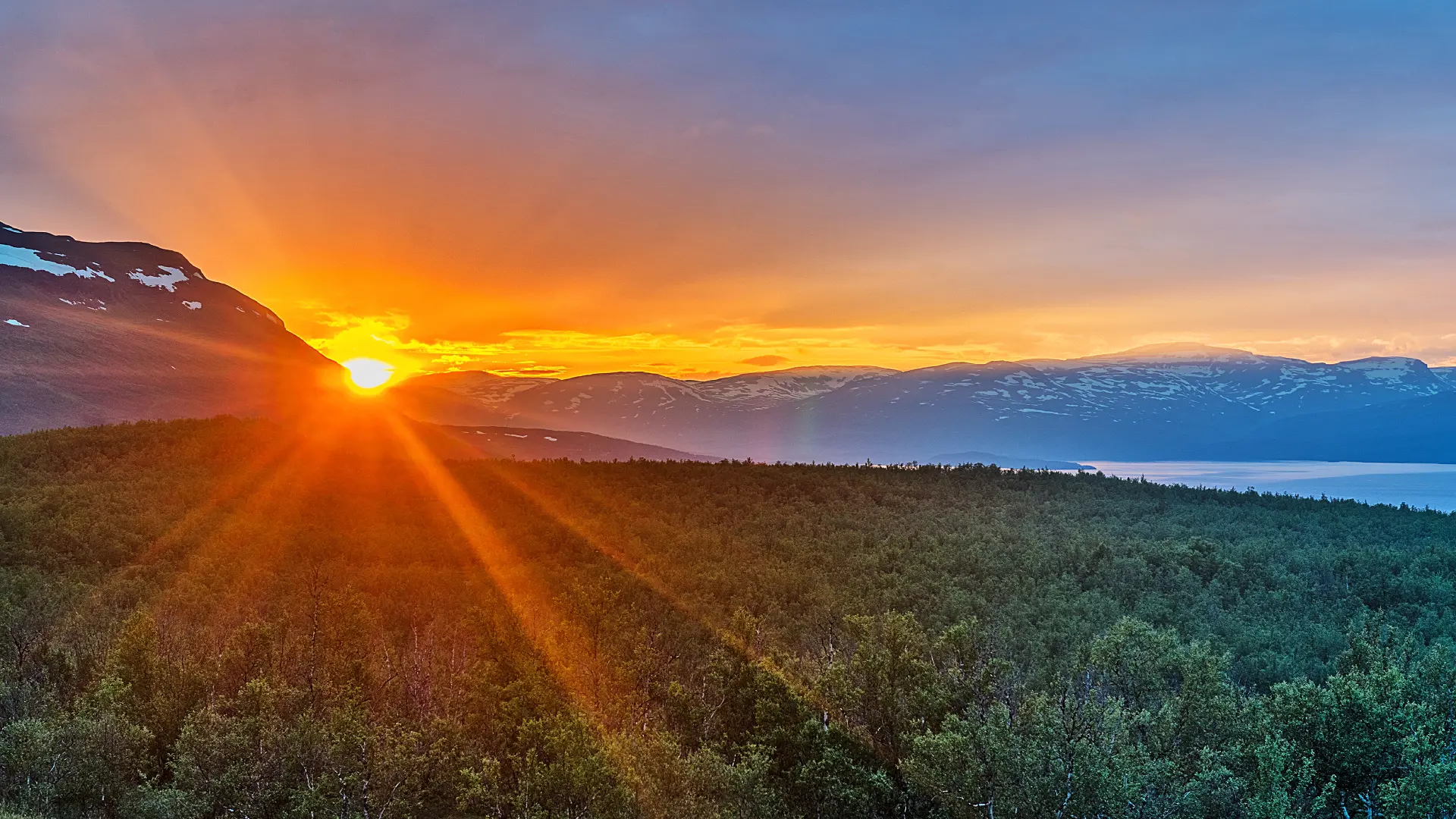Midnight sun low on the horizon over a summer landscape in Abisko National Park, Sweden.