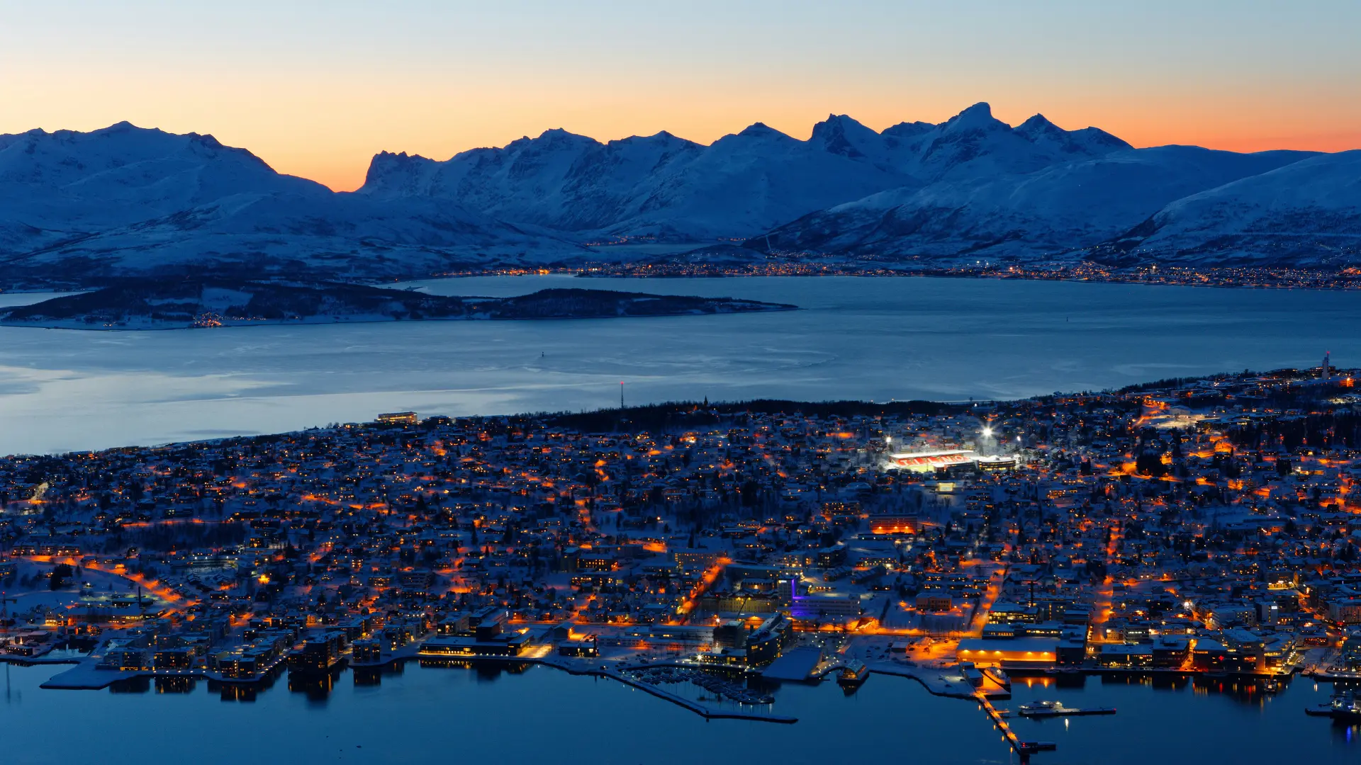 City of Tromsø in northern Norway with surrounding mountains and sea during winter twilight